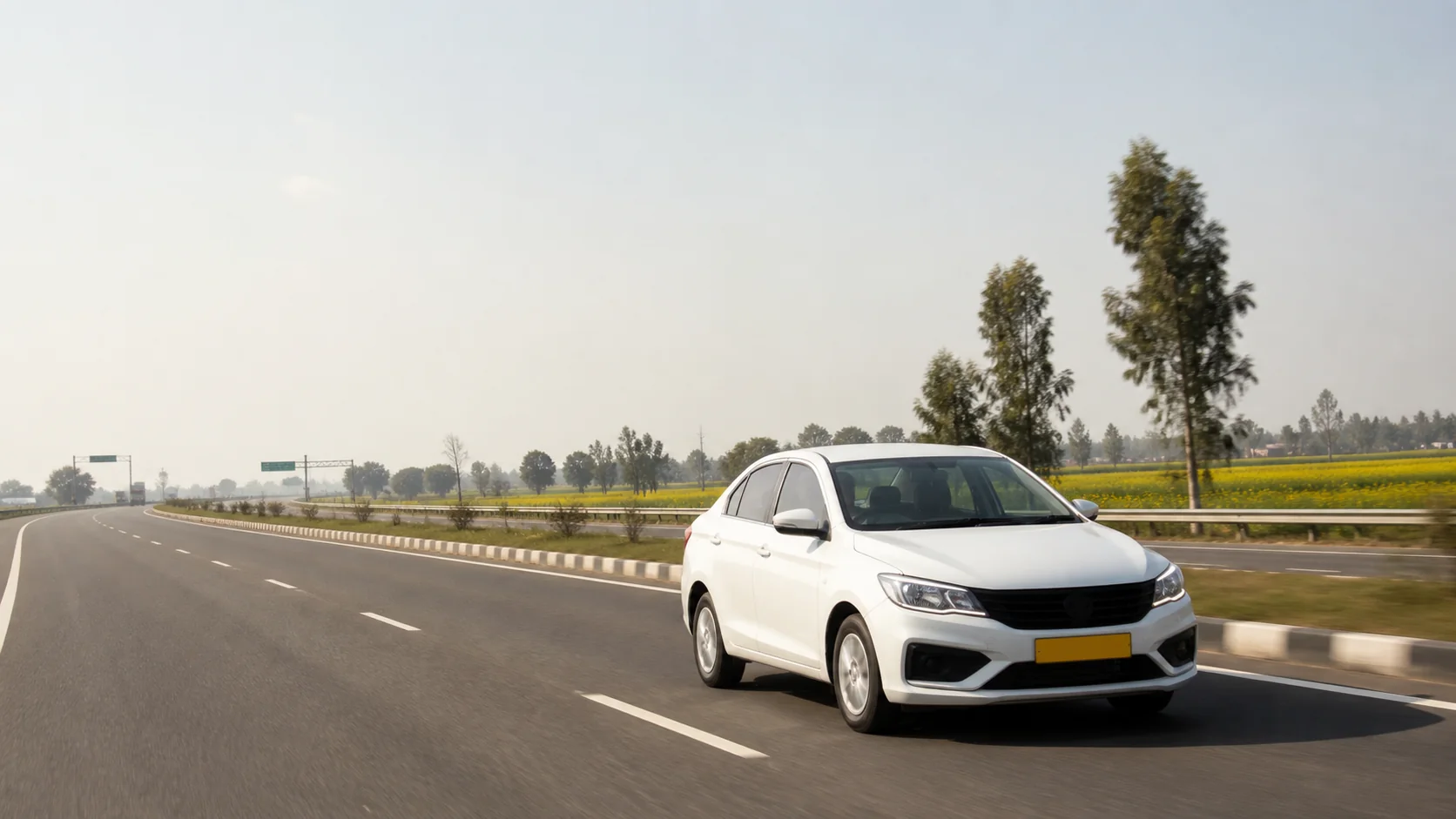 White Indian taxi on a divided Punjab highway beside mustard fields
